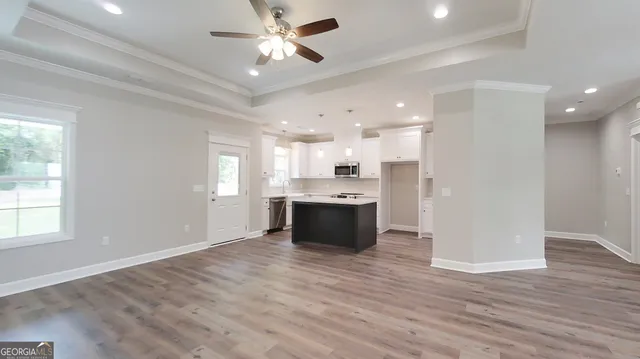 a large white kitchen with a large window stainless steel appliances and wooden floor