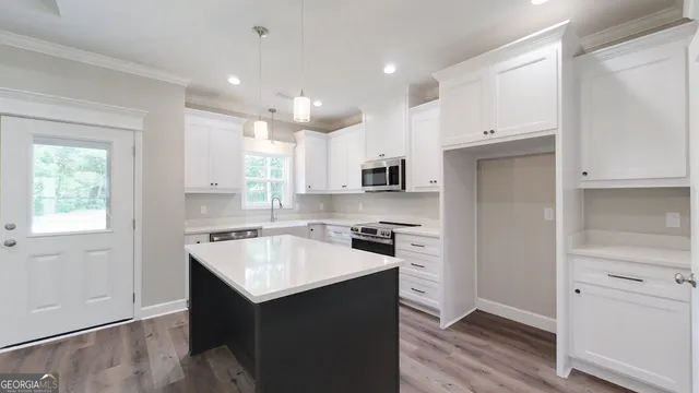 a kitchen with a sink dishwasher a stove and white cabinets with wooden floor