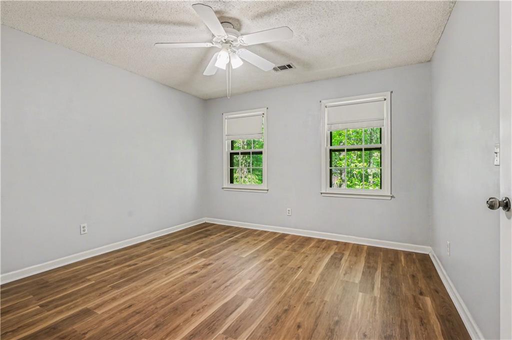 1527 Ridgewood Drive Southwest Lilburn, GA 30047 - Photo 16 of 19 an empty room with wooden floor chandelier fan and windows