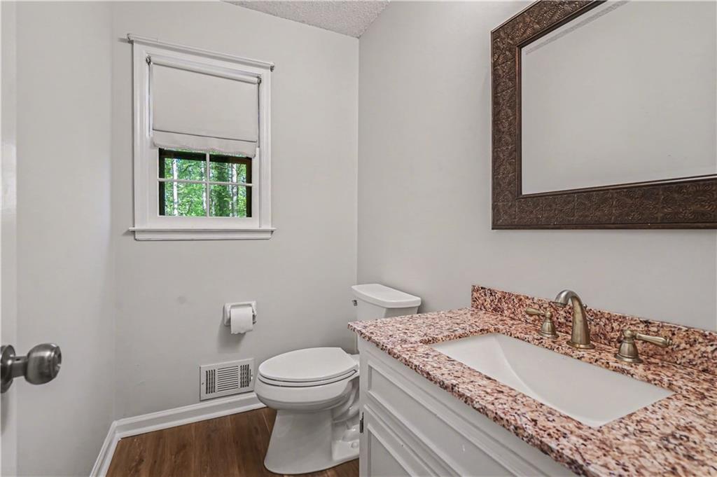 1527 Ridgewood Drive Southwest Lilburn, GA 30047 - Photo 8 of 19 a bathroom with a granite countertop sink a toilet and a mirror