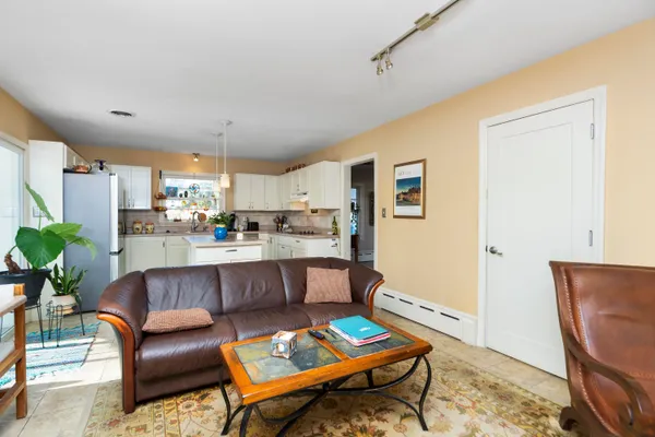 a living room with stainless steel appliances kitchen island granite countertop furniture and a rug