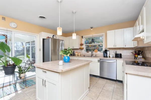 a kitchen with stainless steel appliances granite countertop a refrigerator a sink dishwasher and white cabinets with wooden floor