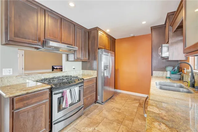 a kitchen with stainless steel appliances granite countertop a stove a refrigerator and a sink