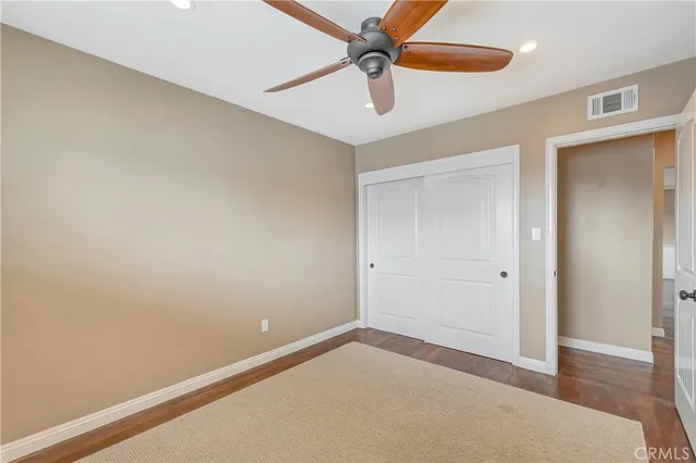 an empty room with a ceiling fan and wooden floor