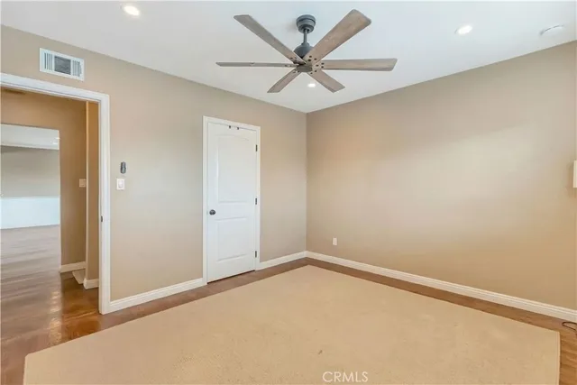 an empty room with wooden floor and a ceiling fan