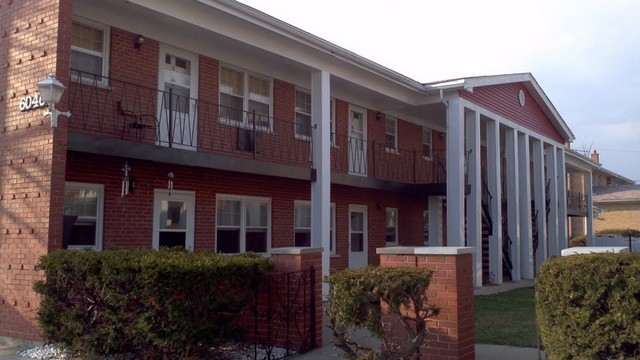 a view of a brick building with many windows and plants