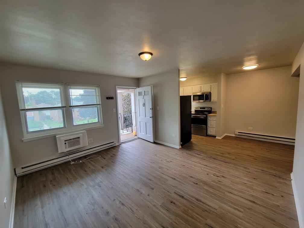 6048 West Pershing Road, Unit 8 Cicero, IL 60804 - Photo 4 of 7 an empty room with wooden floor and windows