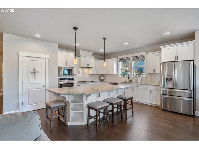 a kitchen with appliances a table and chairs in it