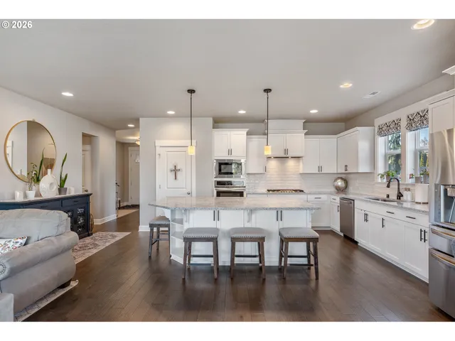 a kitchen with stainless steel appliances kitchen island granite countertop a table chairs and a refrigerator