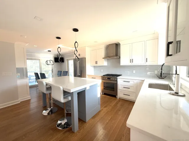 a kitchen with stainless steel appliances kitchen island hardwood floor sink and stove
