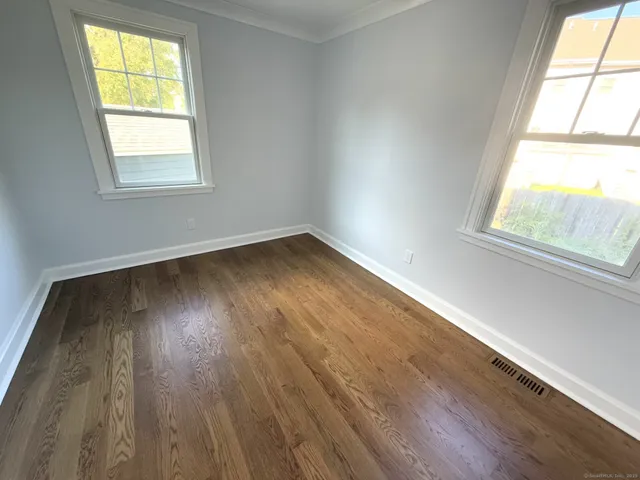 a view of an empty room and wooden floor and a window
