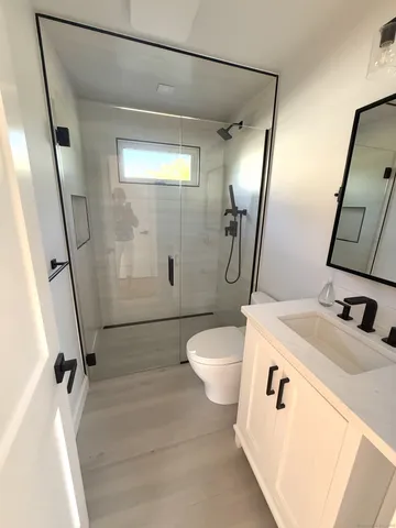 a bathroom with a sink a toilet a mirror and shower
