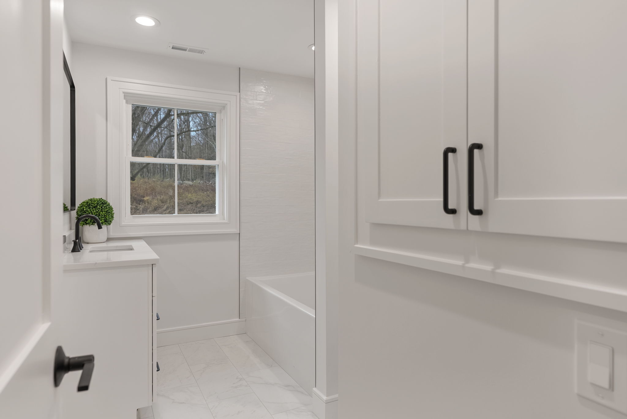 52 Curtis Road Bridgewater, CT 06752 - Photo 15 of 25 Featuring a sleek vanity with stylish black hardware, spacious tub with built-in niche and a linen closet for organized storage.