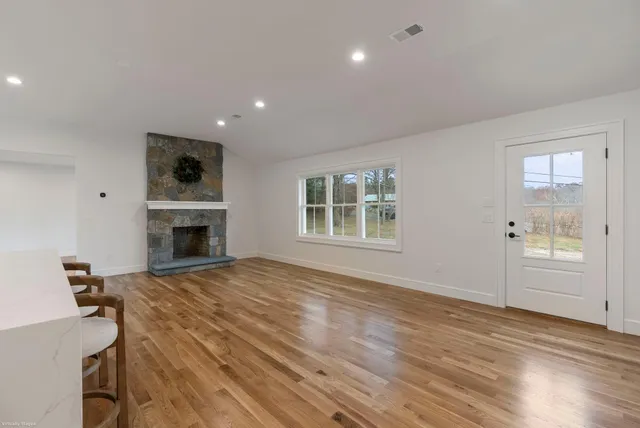 a view of empty room with fireplace and wooden floor