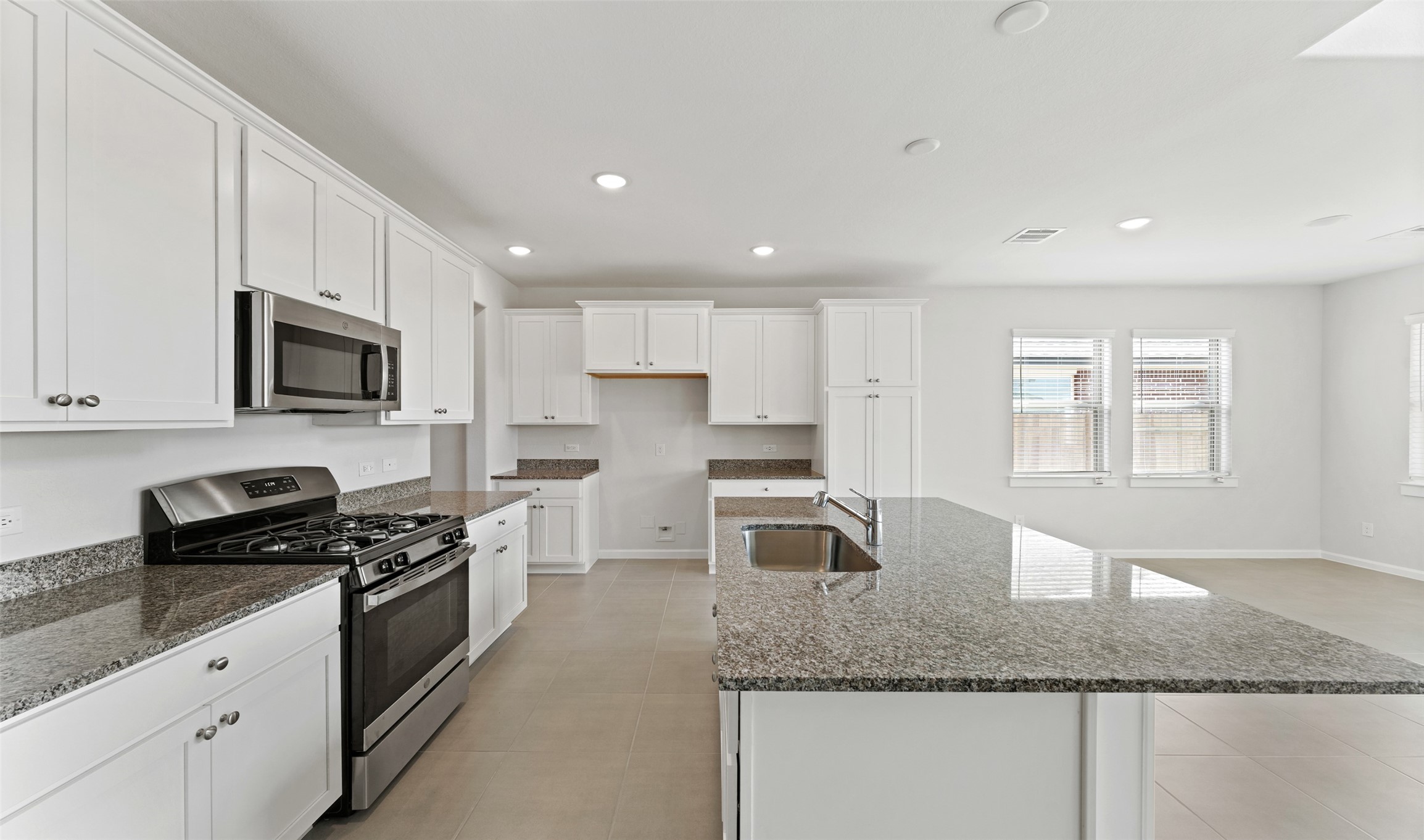 29306 Suncreek Rnch Court Waller, TX 77484 - Photo 6 of 27 a kitchen with granite countertop stainless steel appliances a sink a stove a microwave cabinets and a window