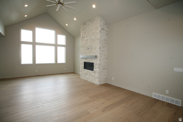 635 East Mountain Road North Ogden, UT 84414 - Photo 9 of 33 Spacious room featuring vaulted ceilings, a large multi-pane window array, a stacked stone fireplace with a floating mantel, recessed lighting, and wood-finish flooring
