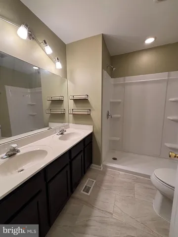 a bathroom with a double vanity sink toilet and shower