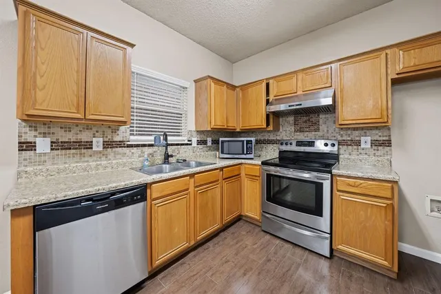 a kitchen with stainless steel appliances granite countertop a sink stove and microwave