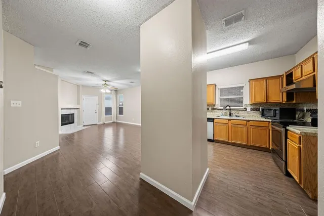a kitchen with granite countertop a refrigerator stove top oven and cabinets