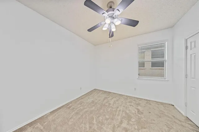 an empty room with a chandelier fan and windows