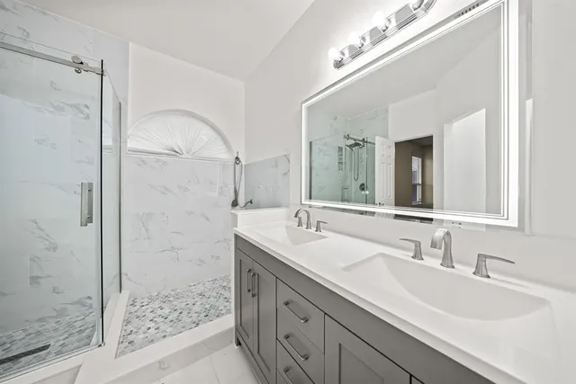 a bathroom with a double vanity sink mirror and shower