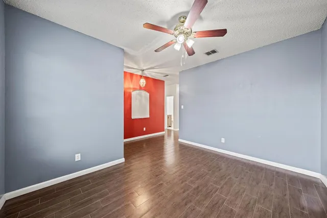 an empty room with wooden floor fan and window