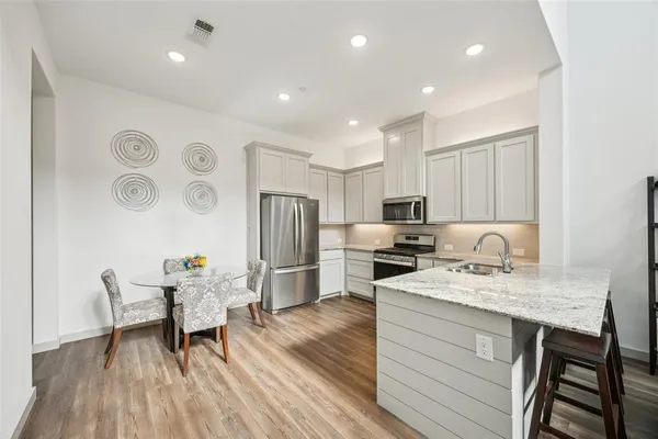 a kitchen with a refrigerator a stove and a dining table with wooden floor