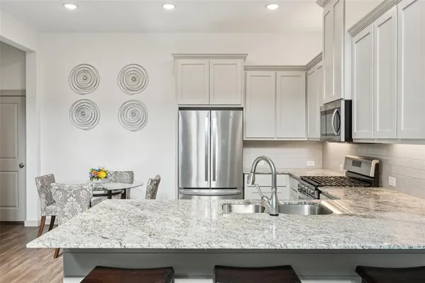 a kitchen with kitchen island granite countertop a sink a stove and refrigerator