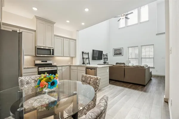 a kitchen with stainless steel appliances kitchen island granite countertop a refrigerator a stove top oven a sink dishwasher and white cabinets with wooden floor