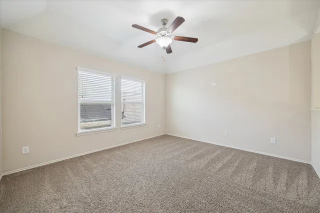 an empty room with window and ceiling fan