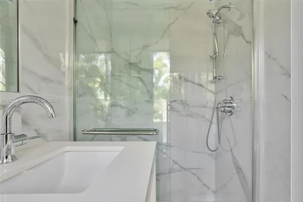 a bathroom with a granite countertop shower a sink and a mirror