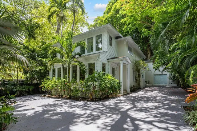 a view of a house with brick walls plants and large tree