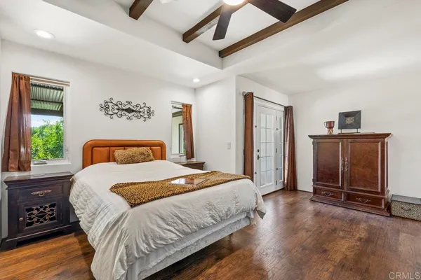 a bedroom with a bed couch and a large window with wooden floor