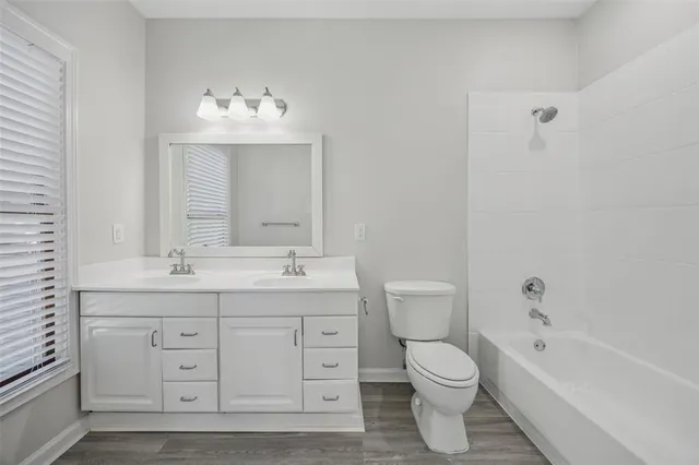 a bathroom with a toilet a sink a mirror a bathtub and vanity