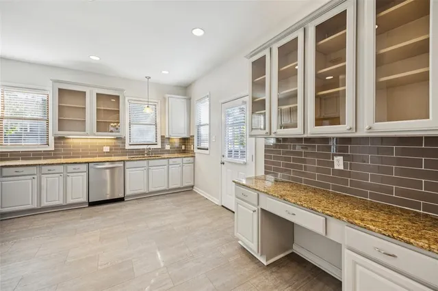 a large kitchen with granite countertop a sink and white cabinets