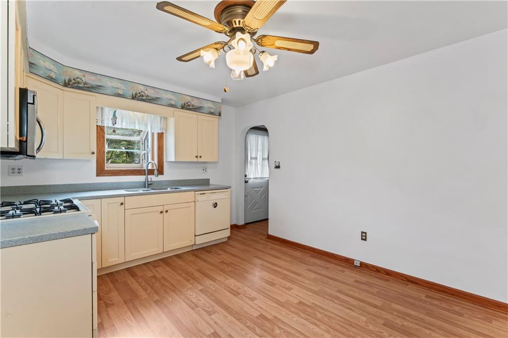 122 Georgetown Road Beaver Falls, PA 15010 - Photo 20 of 44 a kitchen with granite countertop a stove a sink and white cabinets with wooden floor next to windows