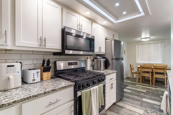 a kitchen with granite countertop a sink a counter space appliances and cabinets