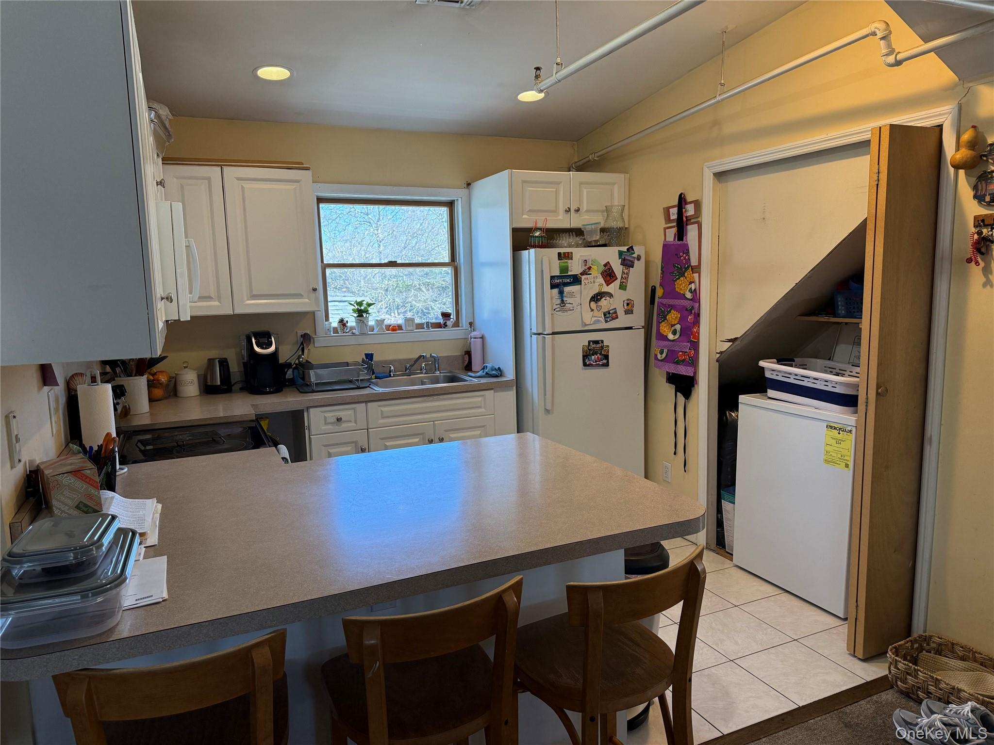 64 Old Riverhead Road Westhampton Beach, NY 11978 - Photo 3 of 9 a kitchen with a table chairs refrigerator and cabinets
