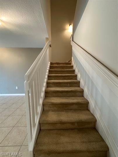 14732 Sutherland Avenue, Unit 332 Naples, FL 34119 - Photo 13 of 33 Stairway with tile patterned flooring and a textured ceiling