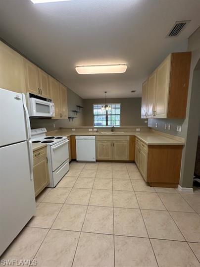 14732 Sutherland Avenue, Unit 332 Naples, FL 34119 - Photo 10 of 33 Kitchen with white appliances, light wood finish cabinets, light countertops, decorative light fixtures, and light tile patterned floors