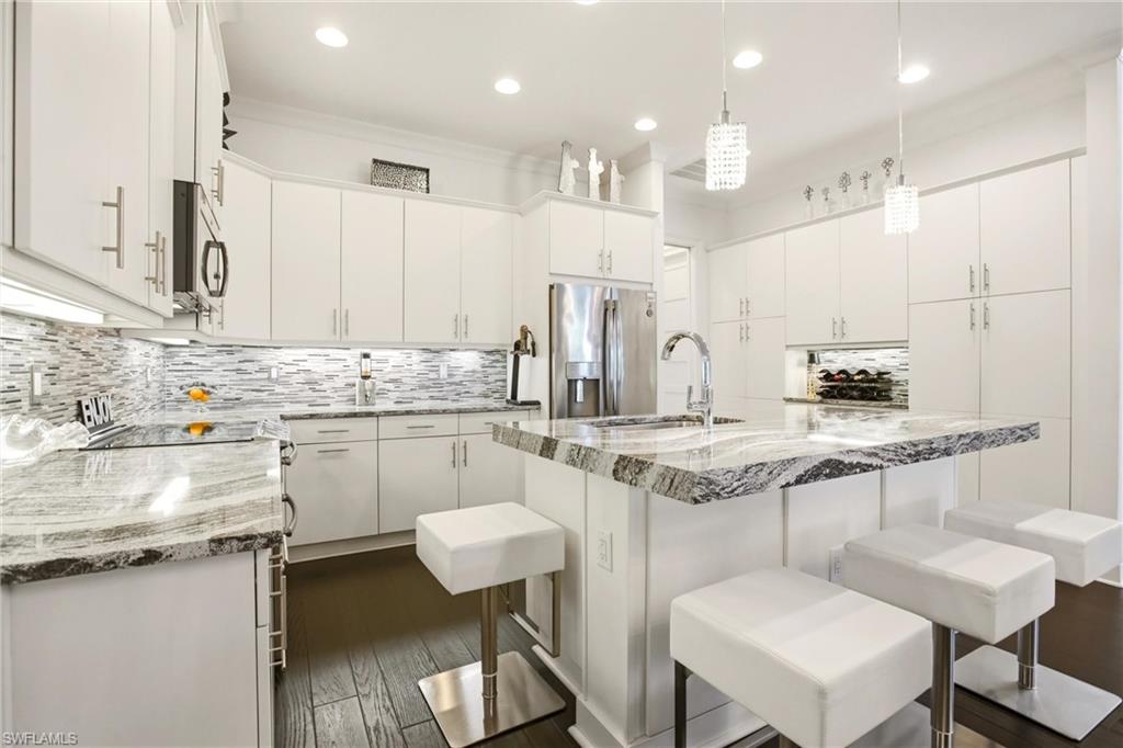 7157 Dominica Drive Naples, FL 34113 - Photo 6 of 39 a kitchen with a sink a stove a refrigerator and white cabinets with wooden floor