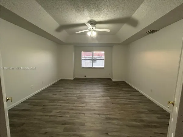 an empty room with wooden floor fan and windows