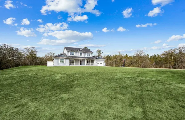 a view of a big house with a big yard and large trees