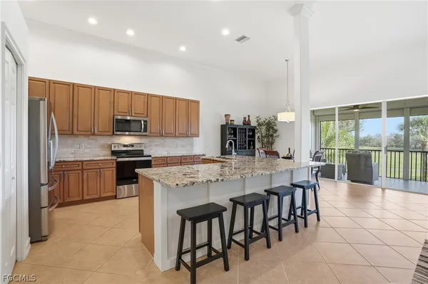 a large kitchen with kitchen island granite countertop a stove a sink a dining table and chairs