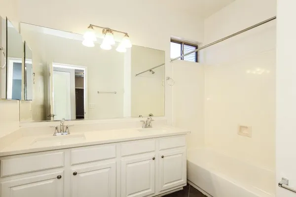 a bathroom with a double vanity sink mirror and a bathtub