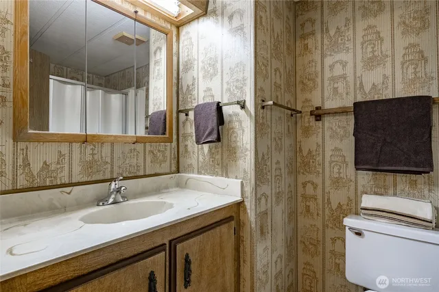 a bathroom with a granite countertop sink a toilet and shower