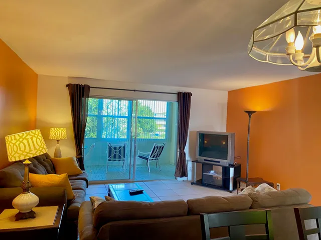 a living room with furniture a flat screen tv and a window