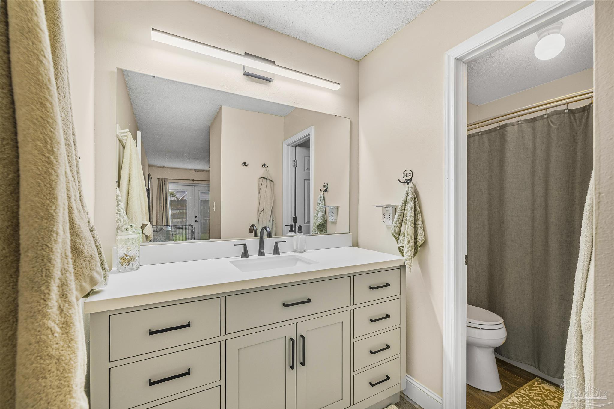 1833 Hunters Path Fort Walton Beach, FL 32547 - Photo 27 of 44 a bathroom with a granite countertop sink toilet a large mirror a vanity and shower