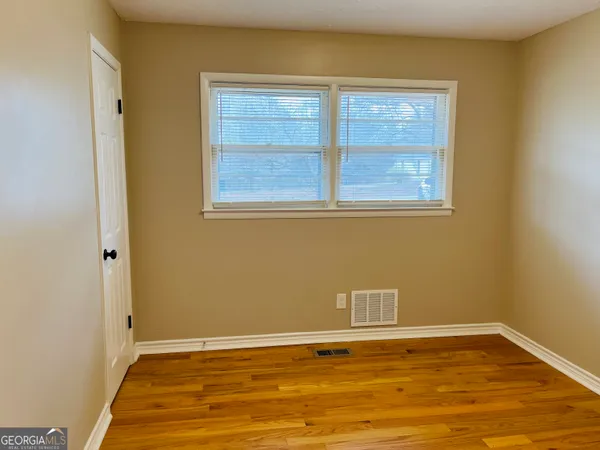 a view of an empty room with wooden floor and a window