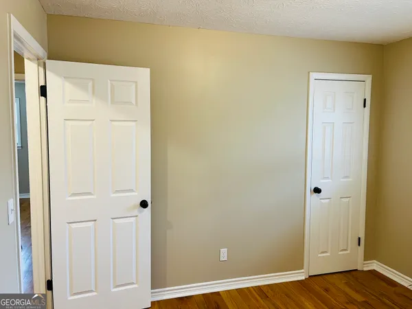 an empty room with wooden floor and closet area